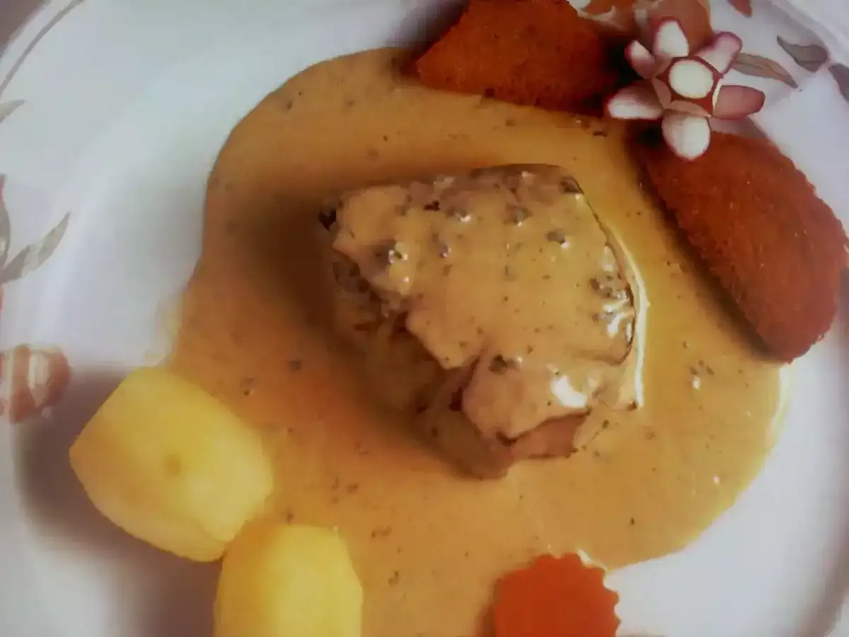 Filete de ternera ba&ntilde;ado en una cremosa salsa a la pimienta, acompa&ntilde;ado de patatas y crujientes tostones.