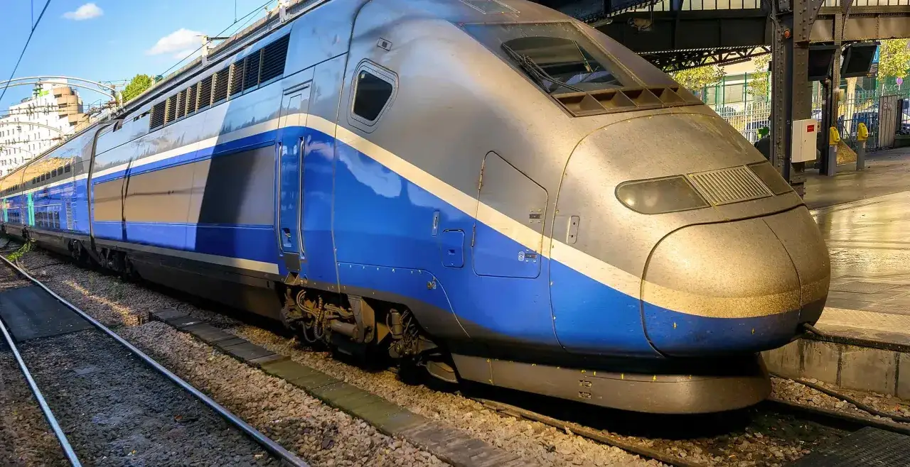 Srebrno-niebieski pociąg TGV na torach, gotowy do podróży z ogromną prędkością.