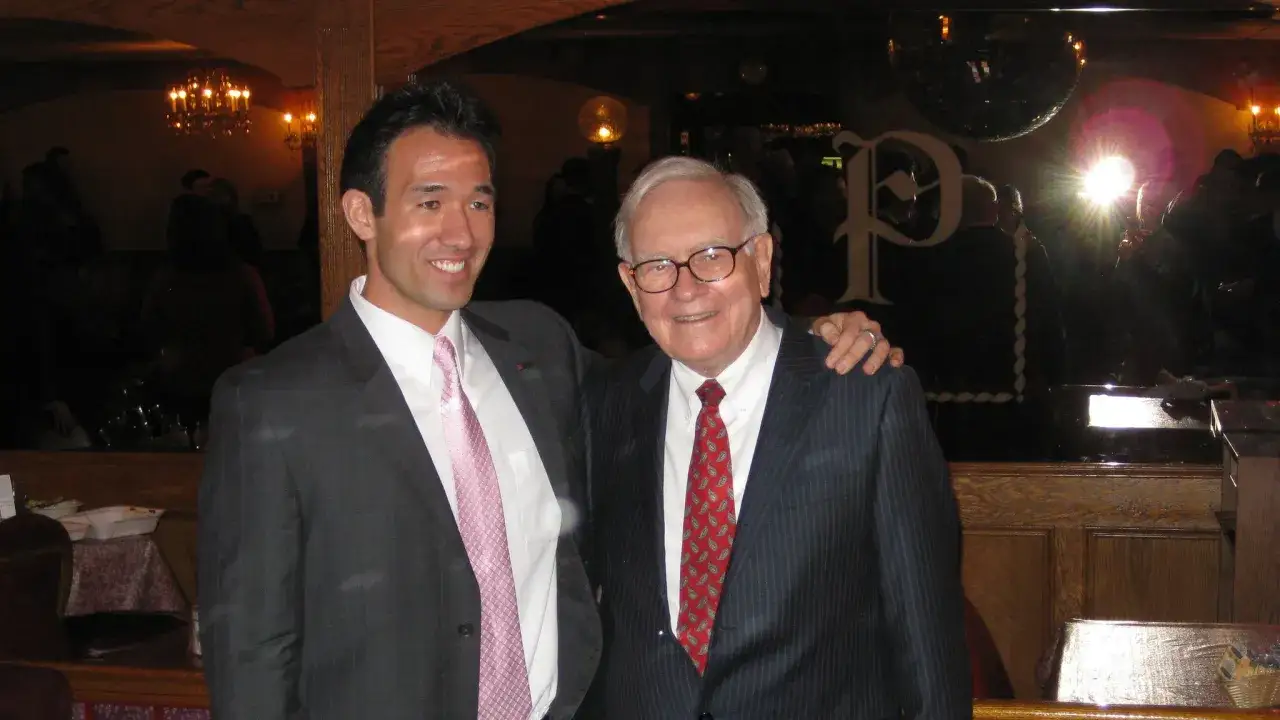 Dw&oacute;ch mężczyzn w garniturach, jeden z nich to Warren Buffett. Jego wykształcenie jest powszechnie znane, choć na zdjęciu tego nie widać.