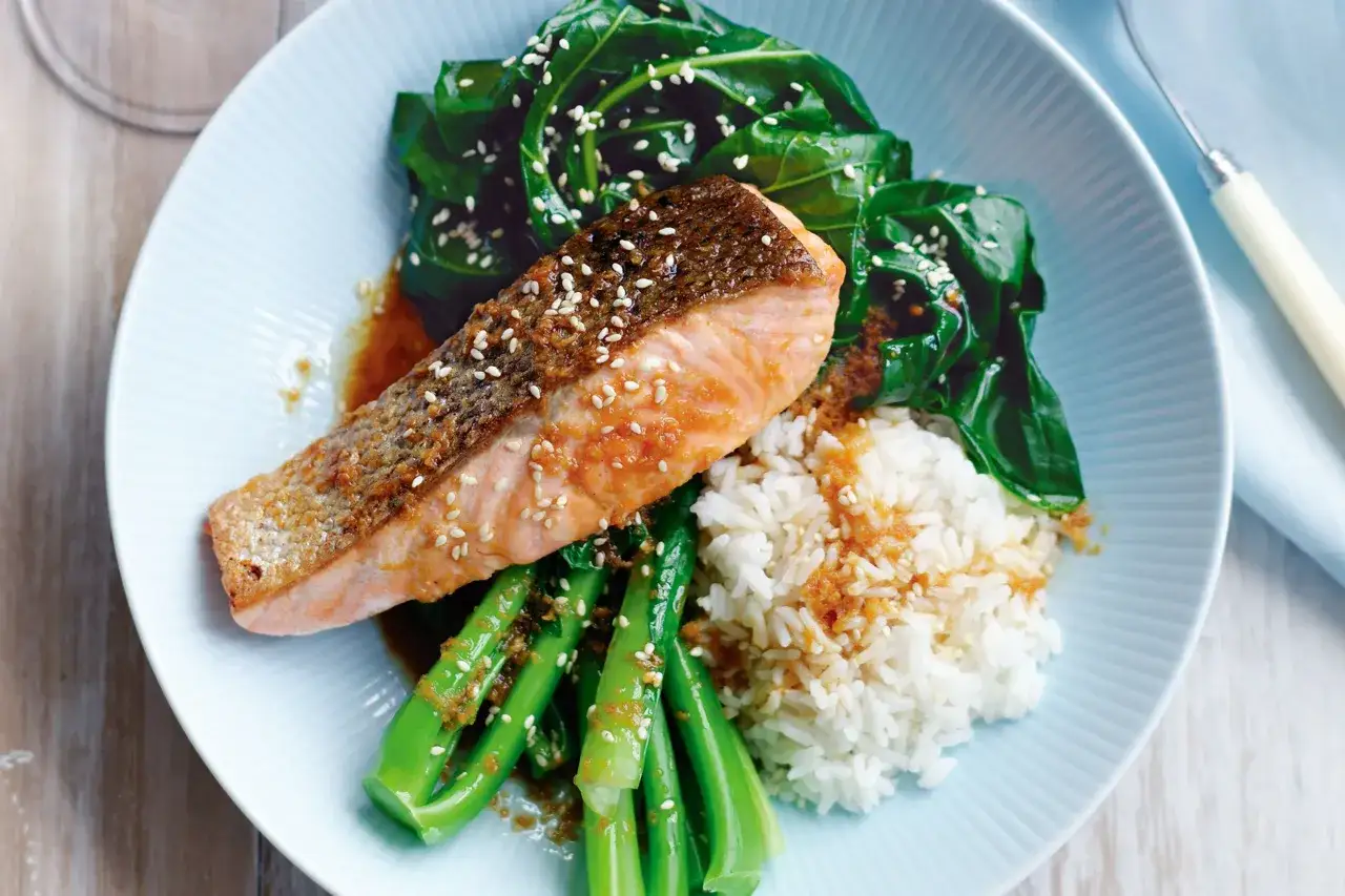 En l&auml;cker asiatisk lax med krispig yta, serverad med &aring;ngad ris och gr&ouml;na gr&ouml;nsaker, toppad med sesamfr&ouml;n.