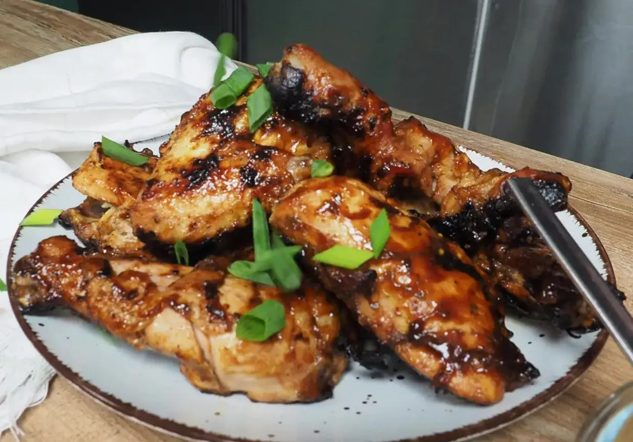 Soczyste kawałki kurczaka w aromatycznej marynacie BBQ, udekorowane szczypiorkiem. Idealne na grilla!