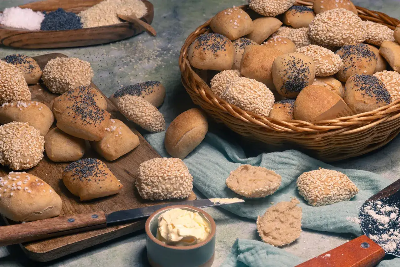Frisch gebackenes Laugenkonfekt selber machen: Kleine Br&ouml;tchen mit Sesam und Mohn, dazu Butter.