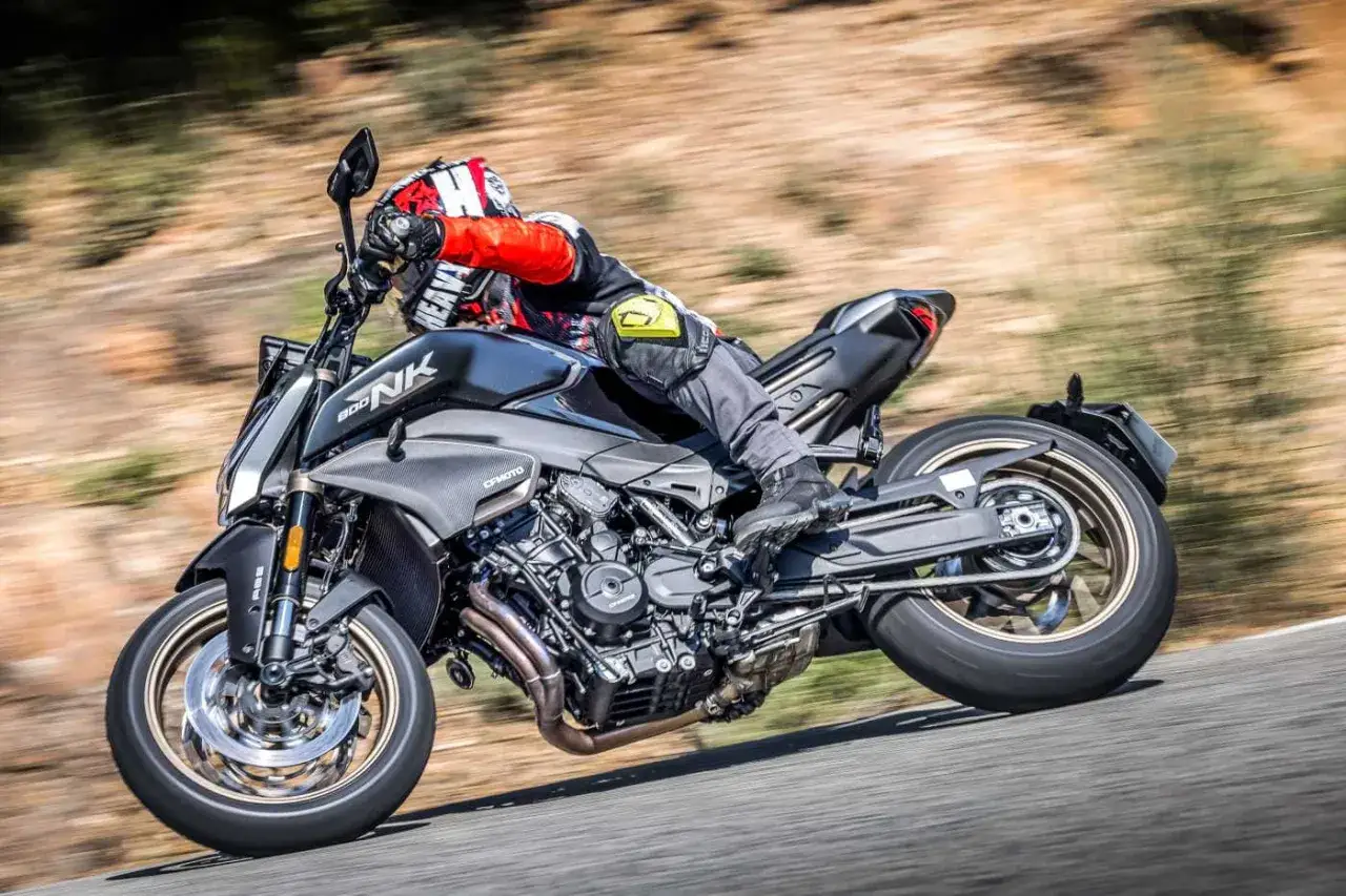 Un motociclista in piega su una CFMOTO 800 NK, con il motore a vista e lo sfondo sfocato che suggerisce velocit&agrave;.