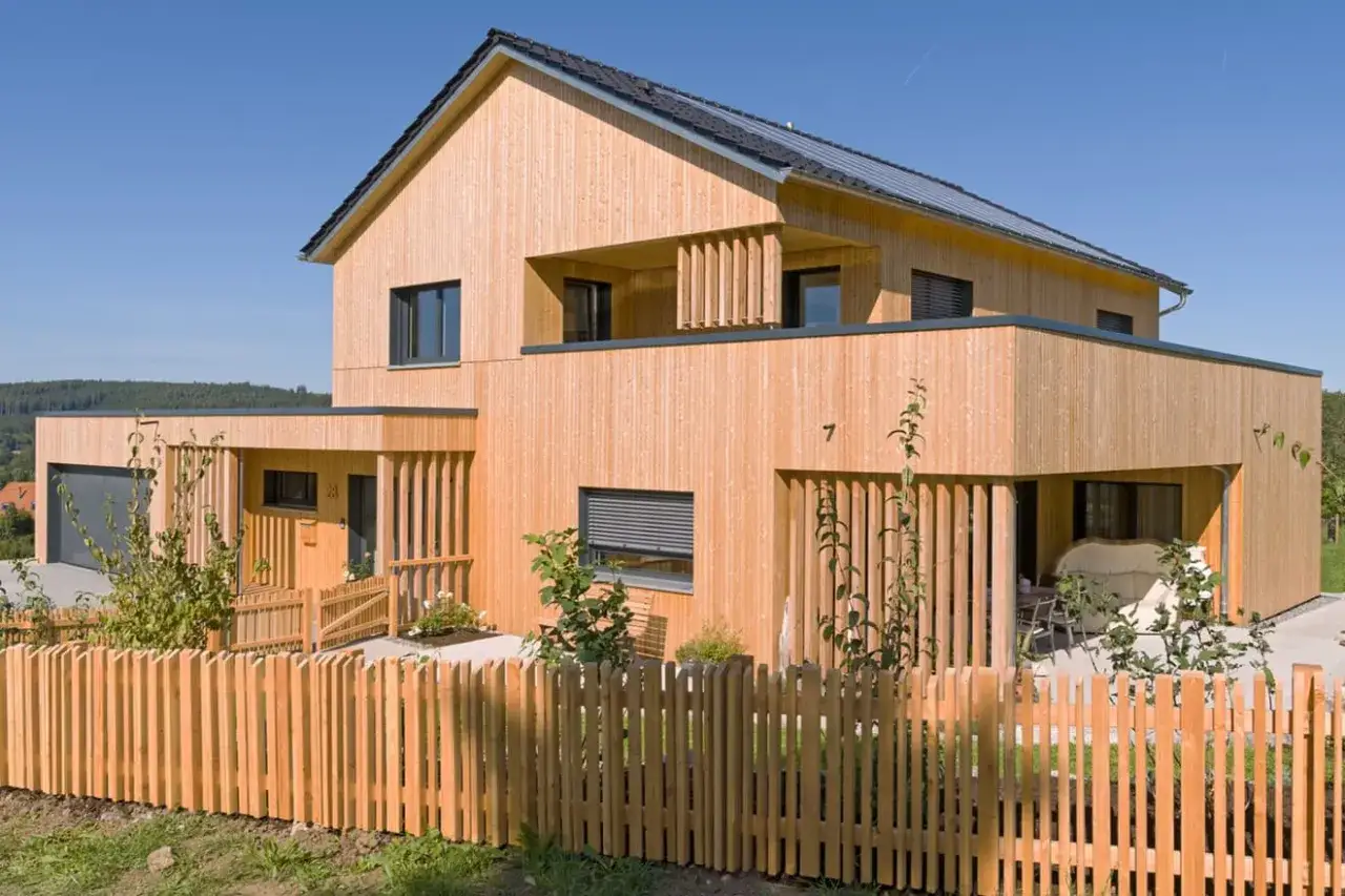 Holzhaus mit moderner Architektur und Solaranlage. Die natürliche Holzfassade verspricht eine lange Lebensdauer eines Fertighauses.