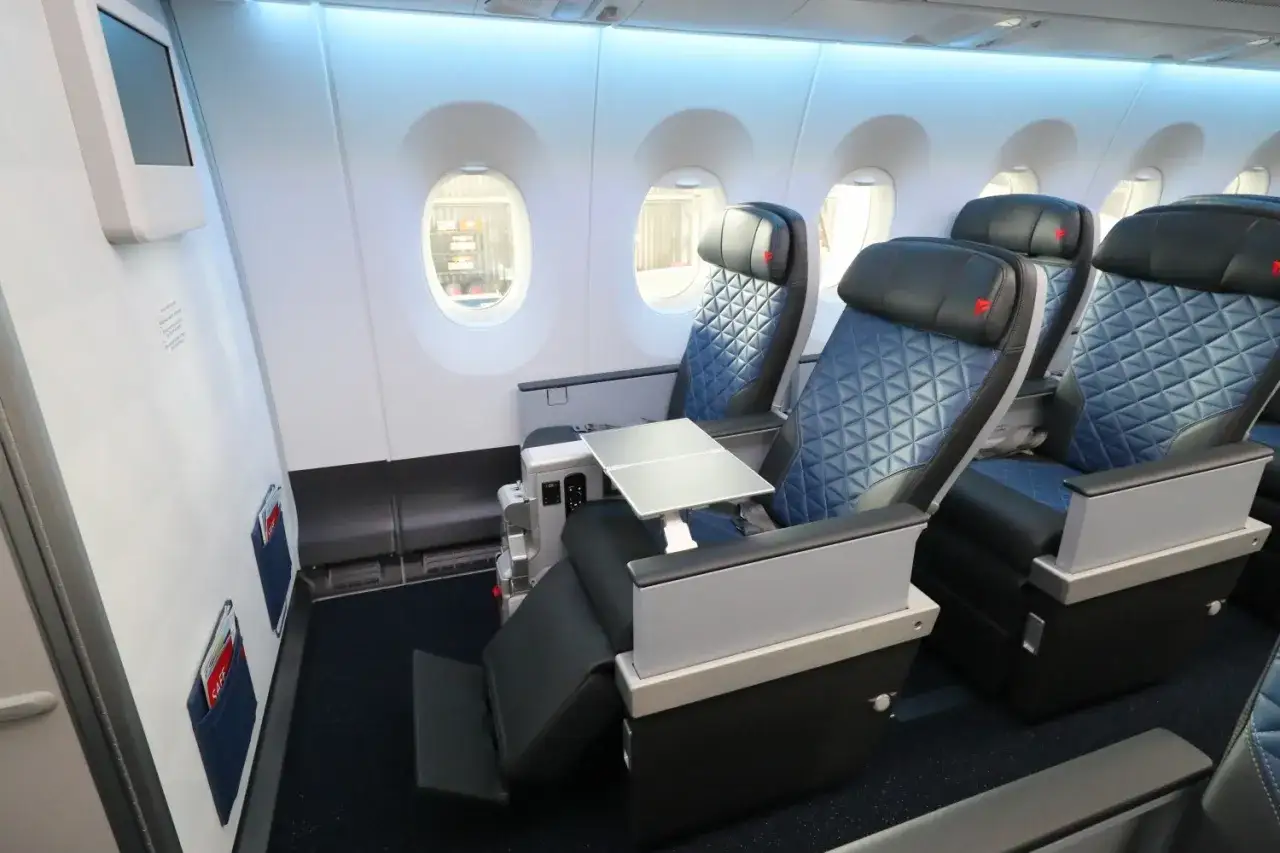 Bequeme Sitze im Flugzeug innen, mit ausklappbaren Tischen und Bildschirmen.