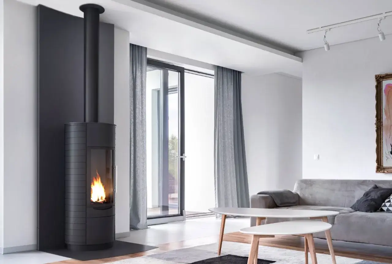 Un poêle à bois moderne avec une cheminée noire et une isolation discrète, créant une ambiance chaleureuse dans un salon lumineux.