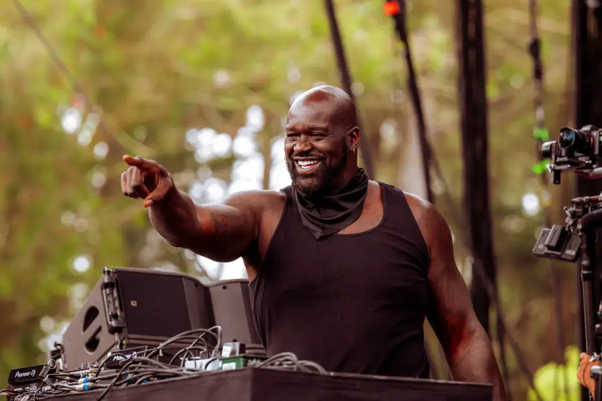 DJ Diesel, czyli Shaquille O'Neal, w czarnej koszulce i z chustą na szyi, wskazuje palcem, bawiąc się na scenie.