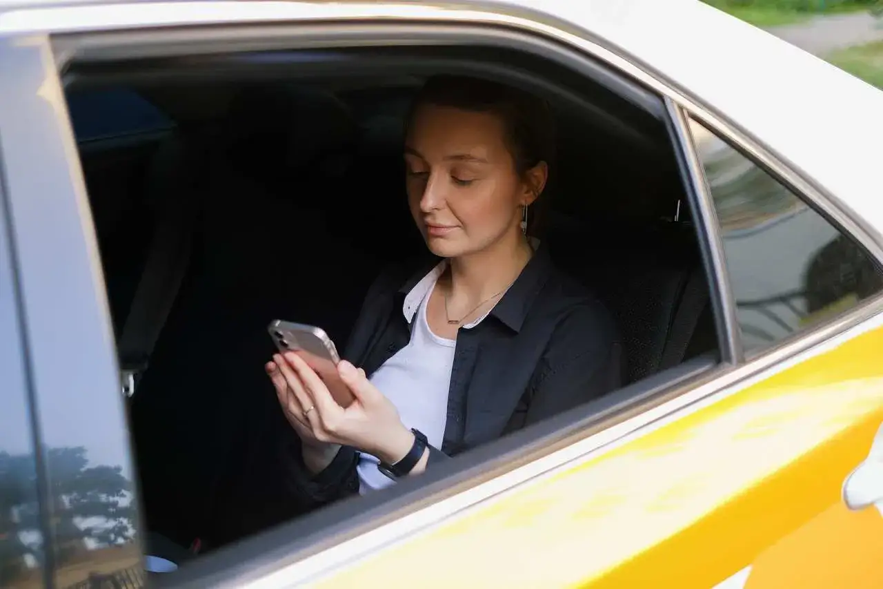Kobieta w samochodzie, korzystająca z telefonu, cieszy się komfortem podróży.
