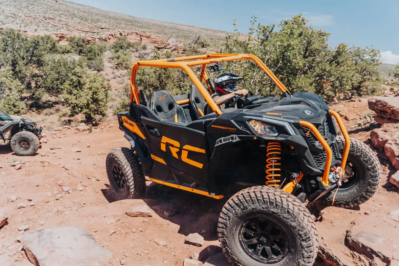 Un conductor con casco maneja un Can-Am Maverick X3 RC, el mejor todoterreno del mundo, por un sendero rocoso y polvoriento.