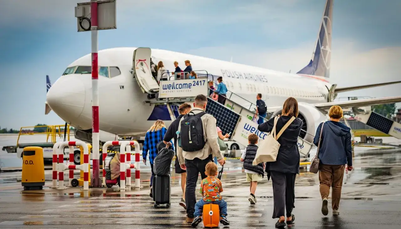 Rodzina wchodzi na pokład samolotu Polish Airlines. To boarding, czyli moment wejścia pasażerów na pokład.