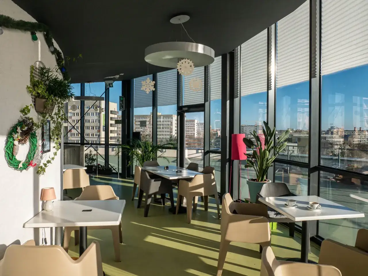 Wnętrze kawiarni z widokiem na miasto. Wesołe dekoracje świąteczne i rośliny tworzą przytulną atmosferę w tej wyjątkowej cafe muzeum we Wrocławiu.