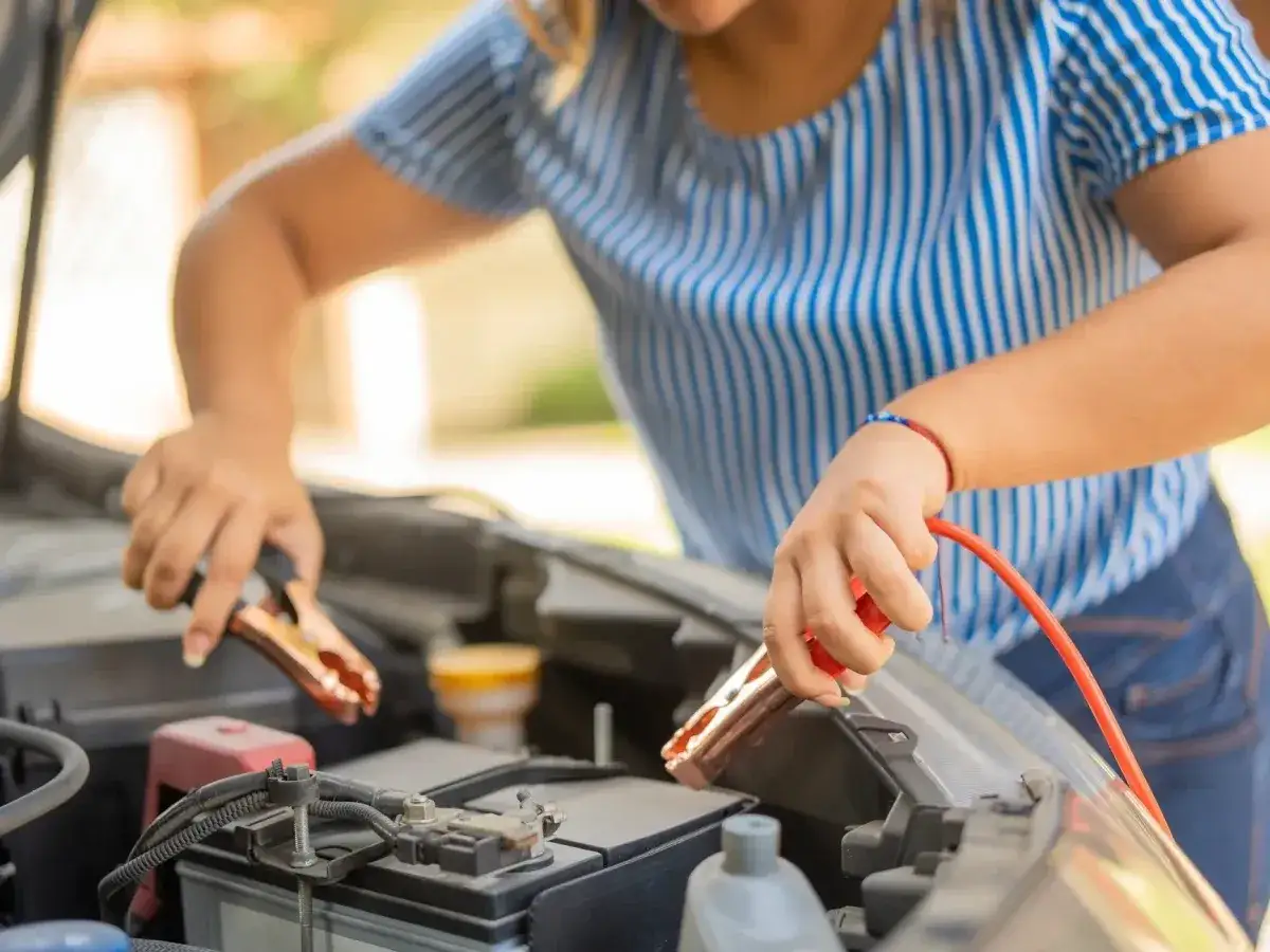 Kobieta podłącza kable do rozładowanego akumulatora. Jak odpalić bez kabli? To pytanie, gdy nagle potrzebujesz uruchomić auto.
