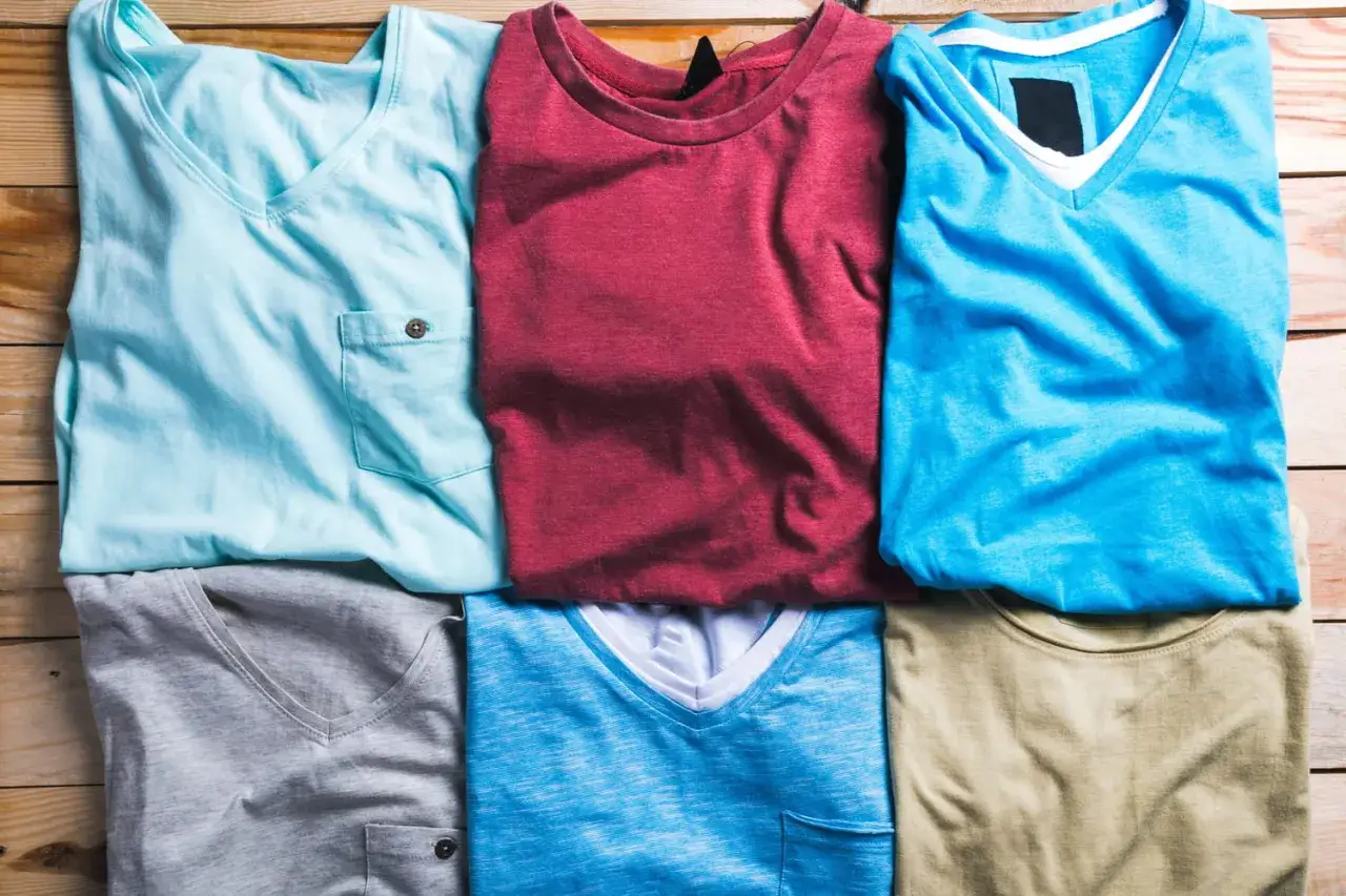 Six t-shirts pliés sur des planches de bois. Apprenez comment repasser du polyester pour un rendu impeccable.