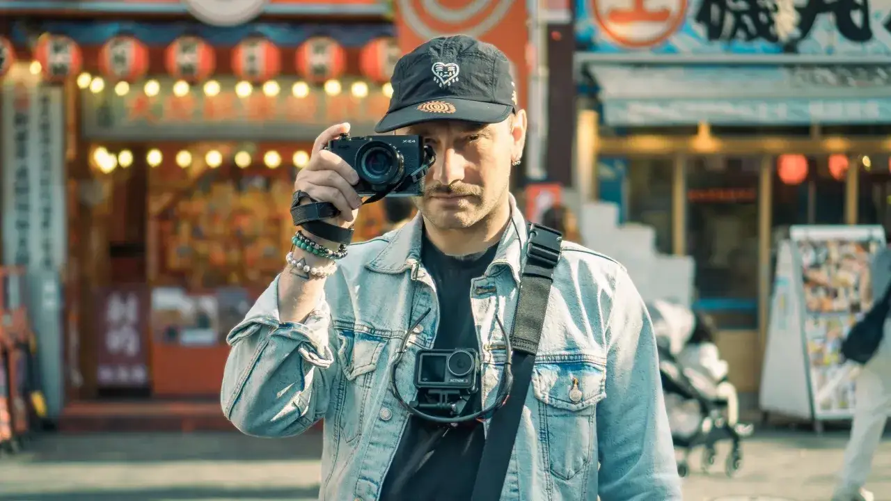 Uomo con Fujifilm X-E4 in mano, pronto a catturare l'atmosfera di un mercato asiatico.
