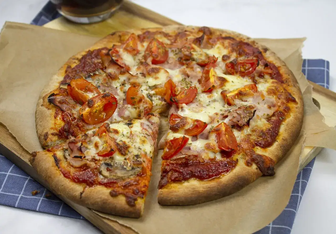 Pyszna pizza z szynką, pomidorkami i serem. Idealna na szybki obiad, zastanawiasz się jaka szynka na pizzę będzie najlepsza? Ta wygląda apetycznie!