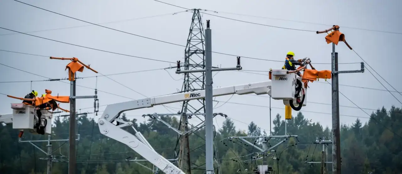 Pracownicy PGE w koszach podnośników naprawiają linię energetyczną. Awaria prądu wymaga szybkiej interwencji.