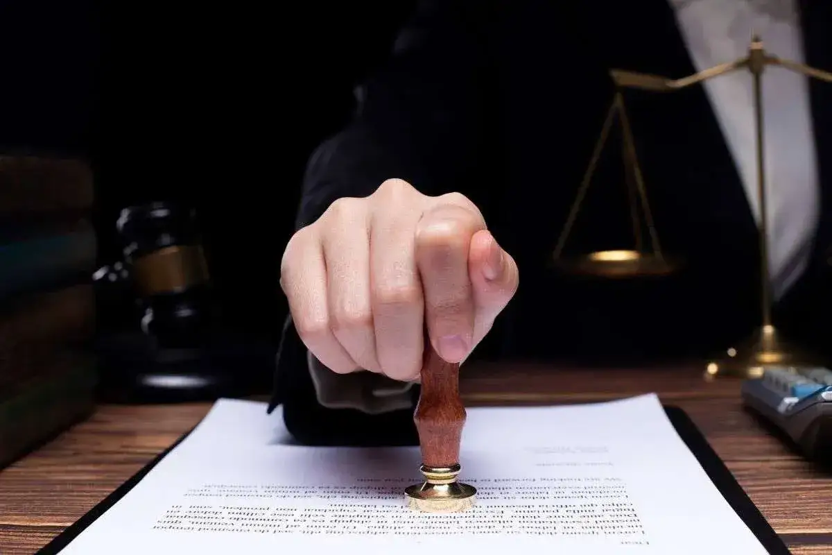 Mano con sigillo su documento legale. Anche se si pu&ograve; rinunciare all'eredit&agrave; dopo averla accettata, questo atto sancisce un accordo.