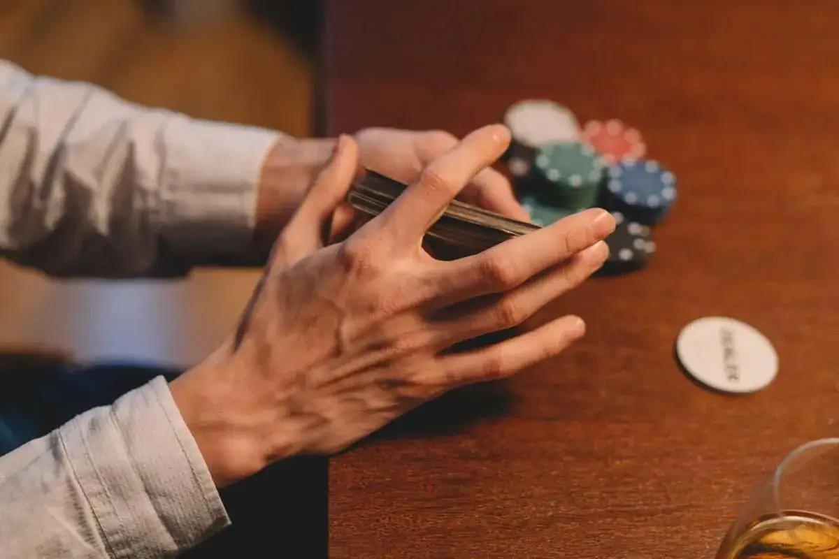 Händer som blandar kort vid ett pokerbord, med marker och en