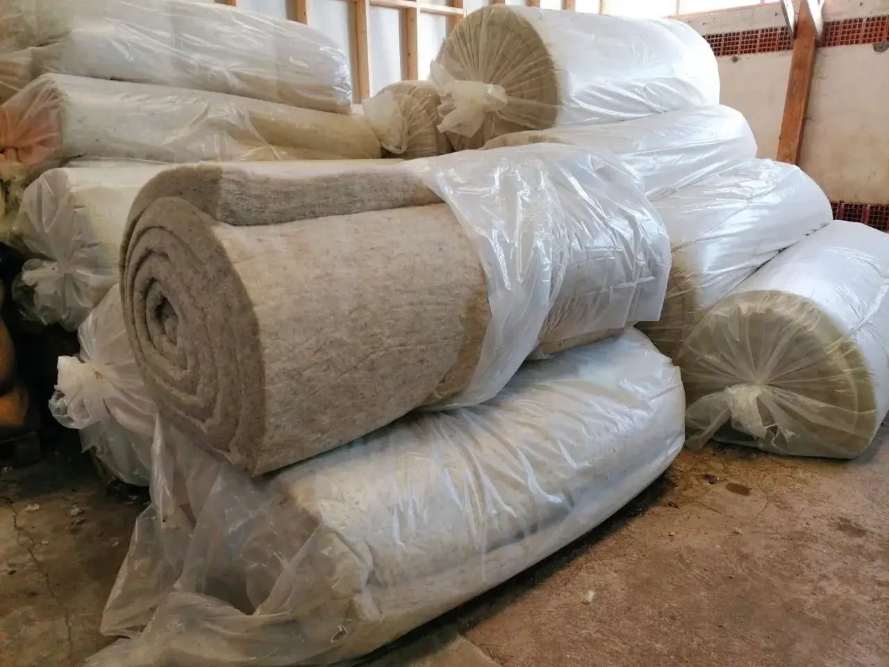 Rouleaux de laine de mouton pour isolation, empilés et emballés dans du plastique transparent.