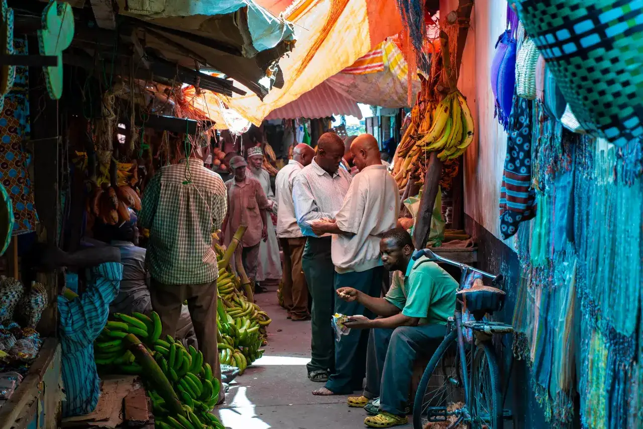Tętniący życiem targ w Stone Town, Zanzibar. Banany, tkaniny i ludzie tworzą barwny obraz.