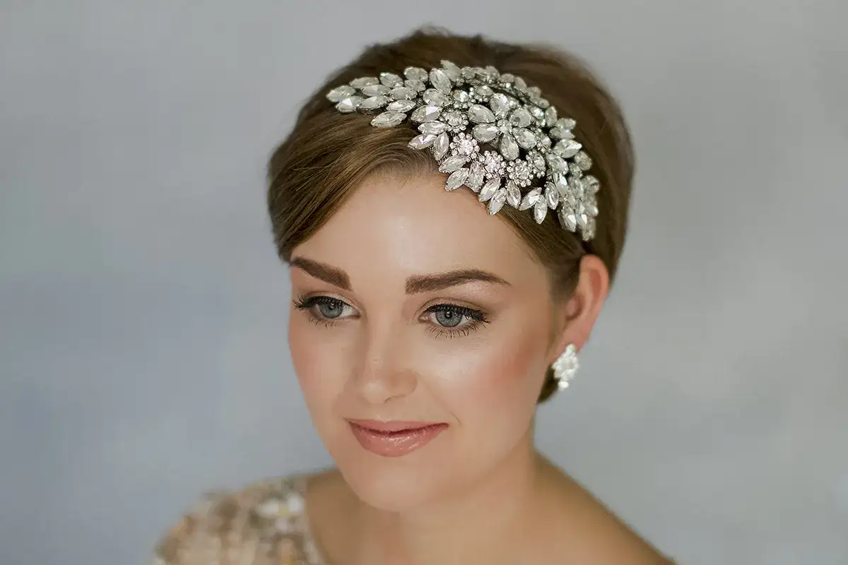 Elegancka fryzura boho krótkie włosy ozdobiona błyszczącą opaską z kryształkami. Delikatny makijaż podkreśla urodę modelki.