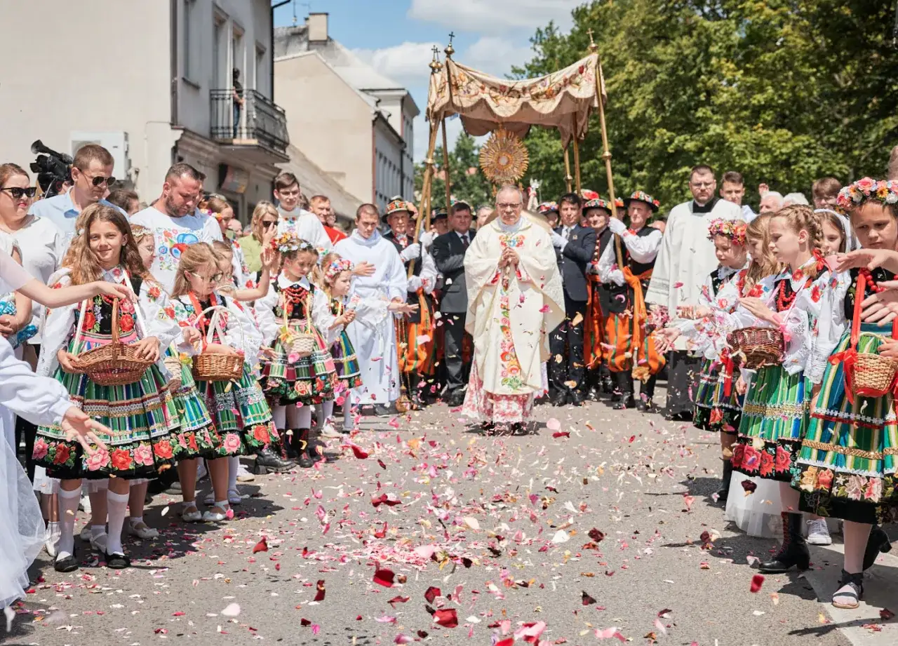 Dzieci w łowickich strojach sypią kwiaty podczas procesji Bożego Ciała. Warto uczestniczyć w tych wydarzeniach, by poczuć tradycję.