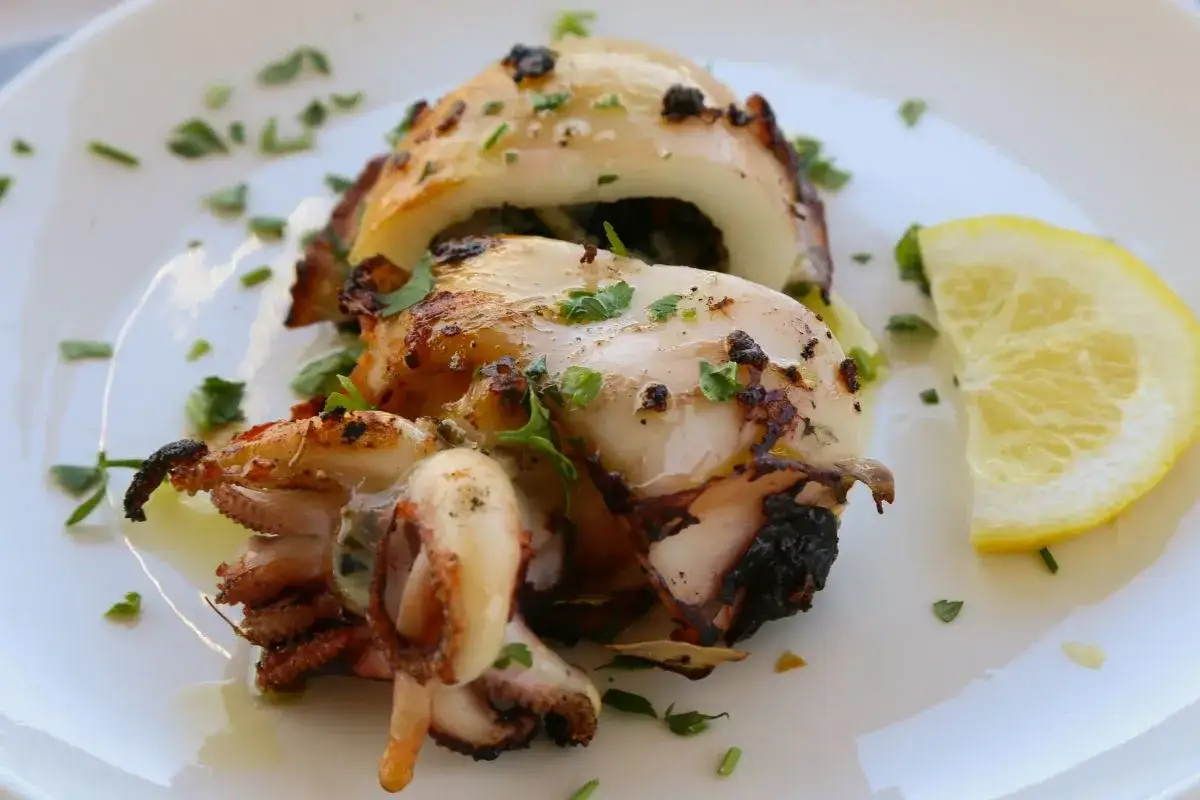 Deliziose seppie alla griglia, ripiene e guarnite con prezzemolo fresco, servite con una fetta di limone.