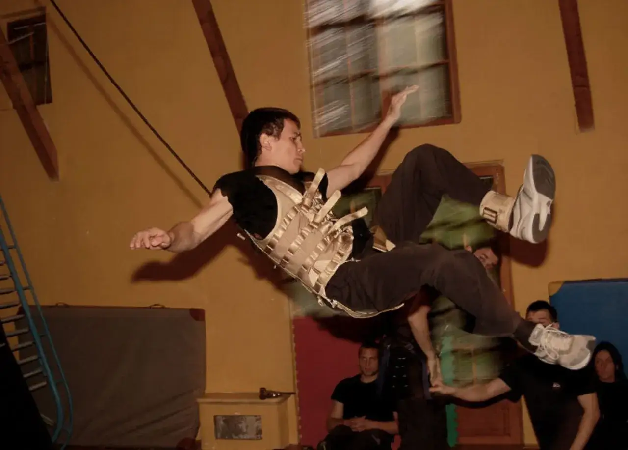 Mężczyzna w kamizelce zabezpieczającej wykonuje akrobację, jak the ultimate stuntman.