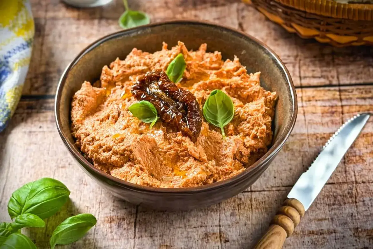 Ein cremiger Tomaten Feta Dip, garniert mit sonnengetrockneten Tomaten und frischem Basilikum, bereit zum Genie&szlig;en.