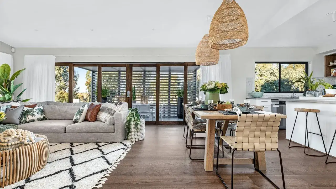 Spazio aperto con idee salotto e sala da pranzo insieme. Divano grigio, tavolo in legno, sedie intrecciate e grandi lampade in rattan.