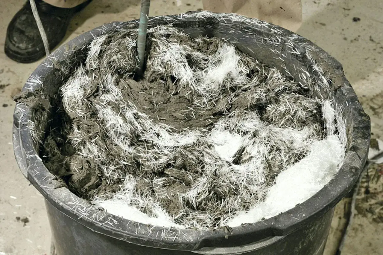 En hink med betong och glasfiber som håller på att blandas.