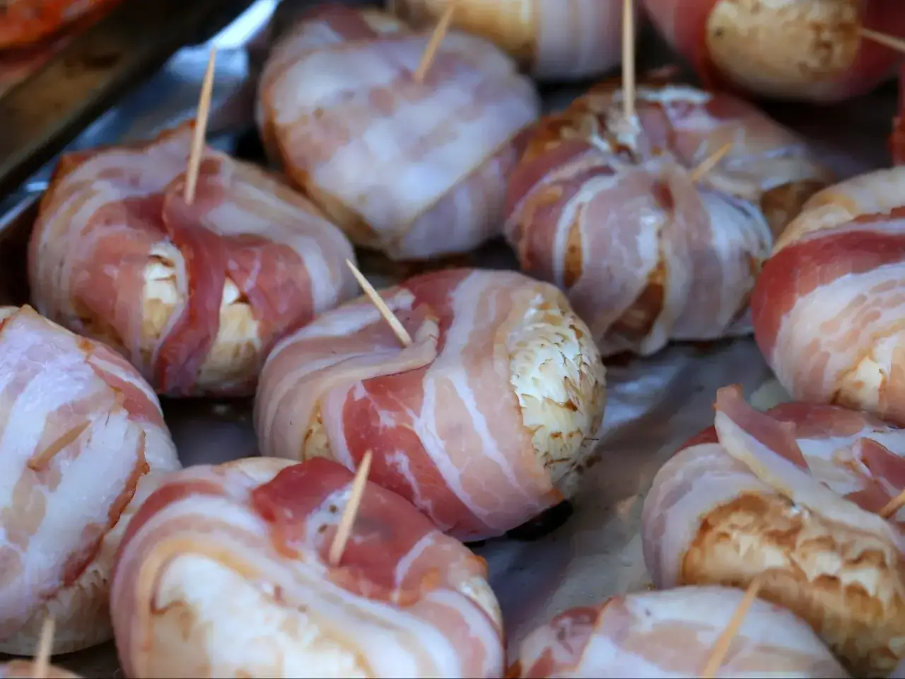 Gotowe do grillowania pieczarki z grilla, owinięte w boczek i zabezpieczone wykałaczkami.