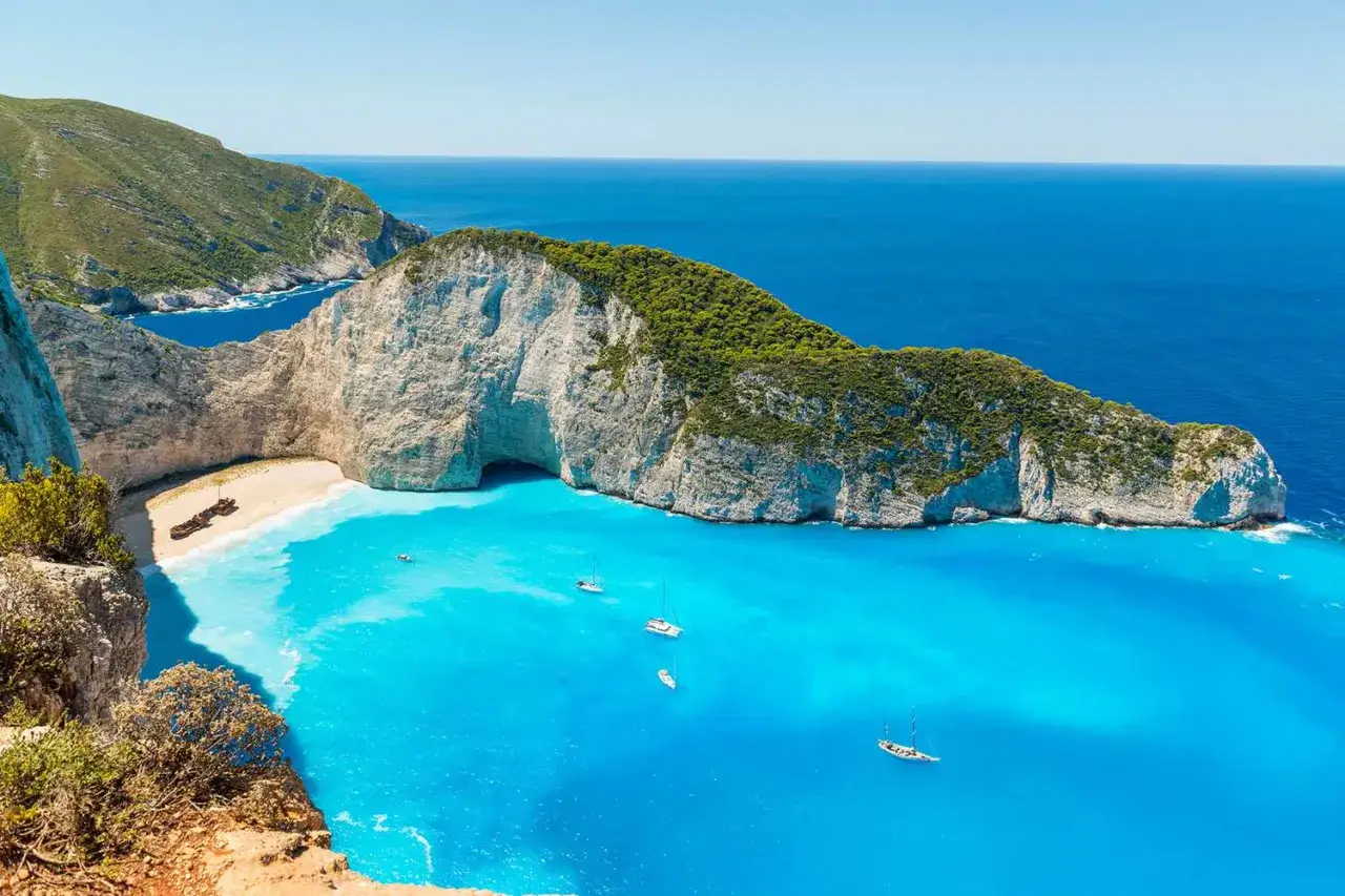 Widok na Navagio, słynną plażę w Grecji, z wrakiem statku na piasku i turkusową wodą.