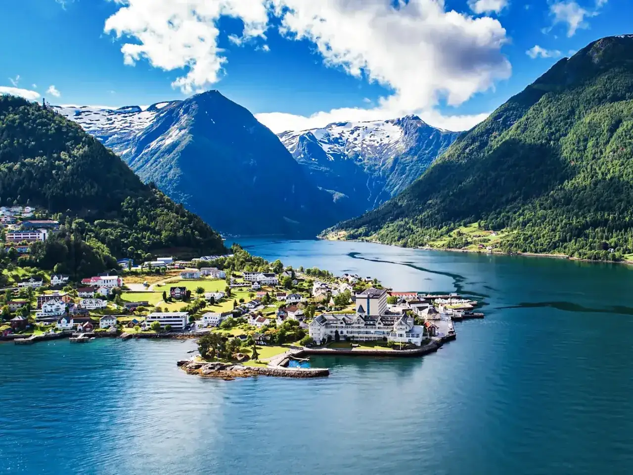 Traumhafte norwegen route 2 wochen: malerisches Dorf am Fjord, umgeben von gr&uuml;nen Bergen und schneebedeckten Gipfeln.