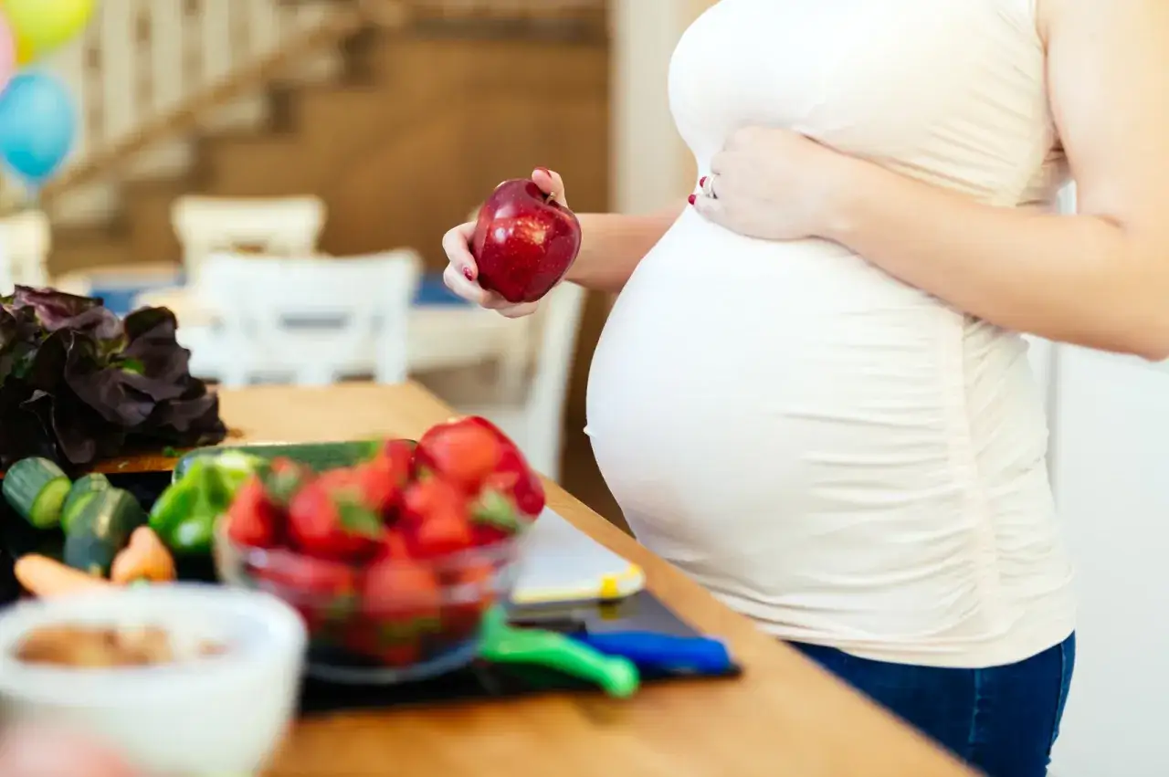 Pancione e frutta fresca, un mix salutare per la **cacca in gravidanza**. La futura mamma sceglie mele e fragole.