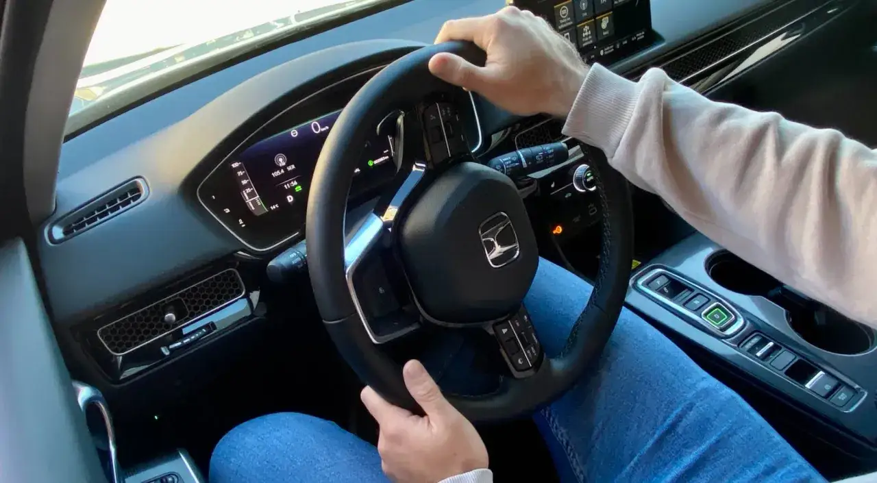 Mano girando el volante en un coche moderno, se escucha un ruido clack clack al girar el volante en parado.