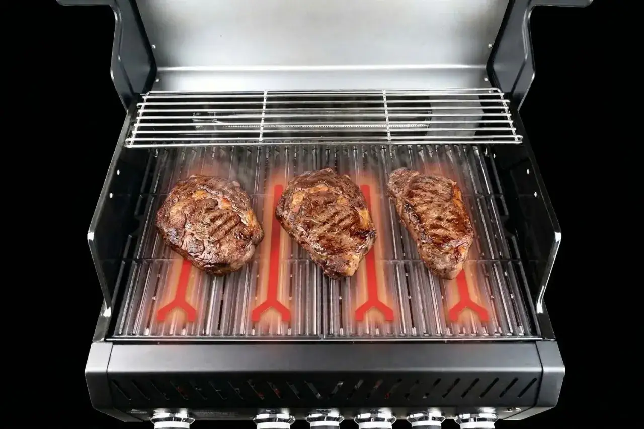 Trzy soczyste steki dojrzewają na ruszcie, a pod nimi żarzą się czerwone elementy grzewcze. Idealne grillowanie na gazie!