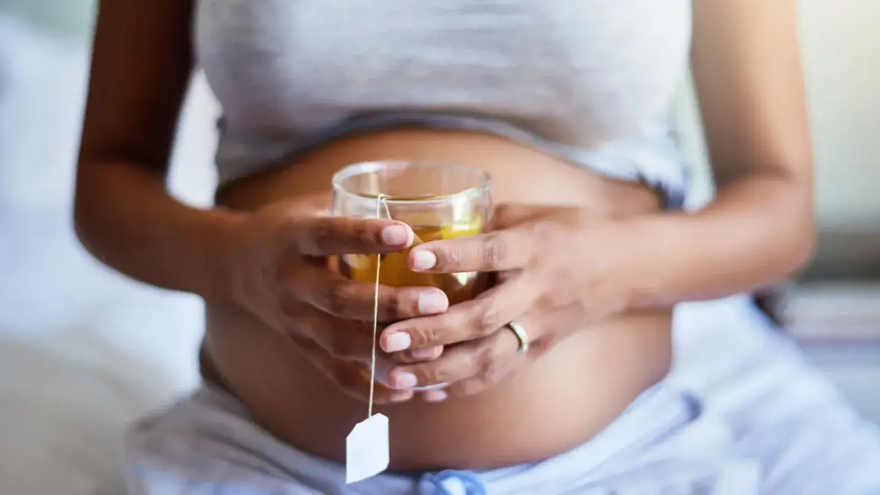 Schwangere Frau hält ein Glas Minztee. Minze in der Schwangerschaft kann bei Übelkeit helfen.