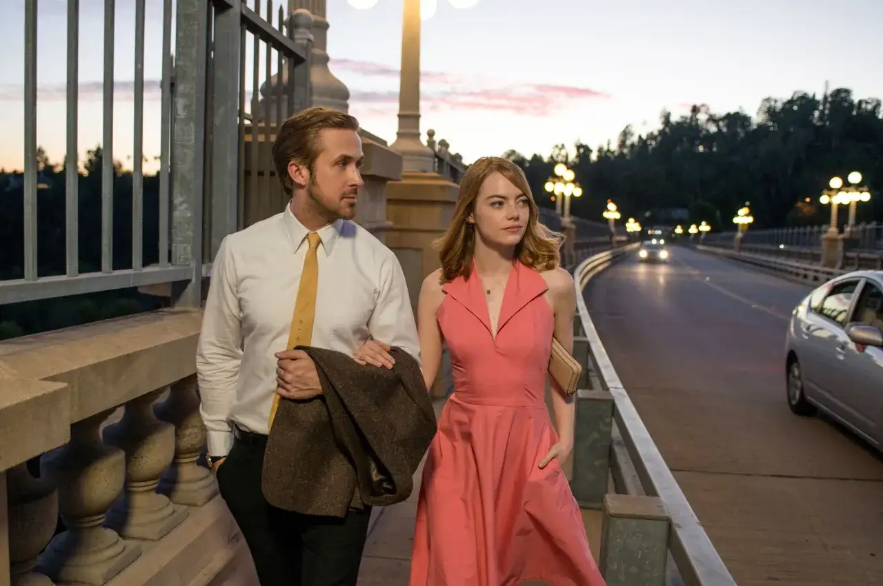 Ryan Gosling i Emma Stone, czyli główna la la land obsada, spacerują po moście o zachodzie słońca.