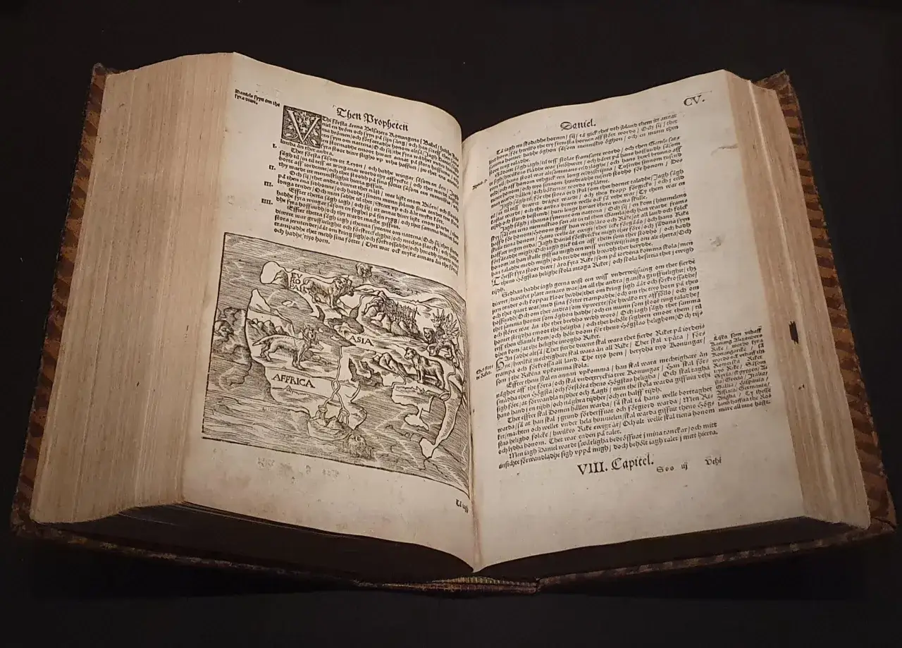 En gammal bok med illustrationer av djur och en karta över Afrika och Asien. Texten är på svenska och handlar om profeter, vilket ger ett visst **mannaminne**.