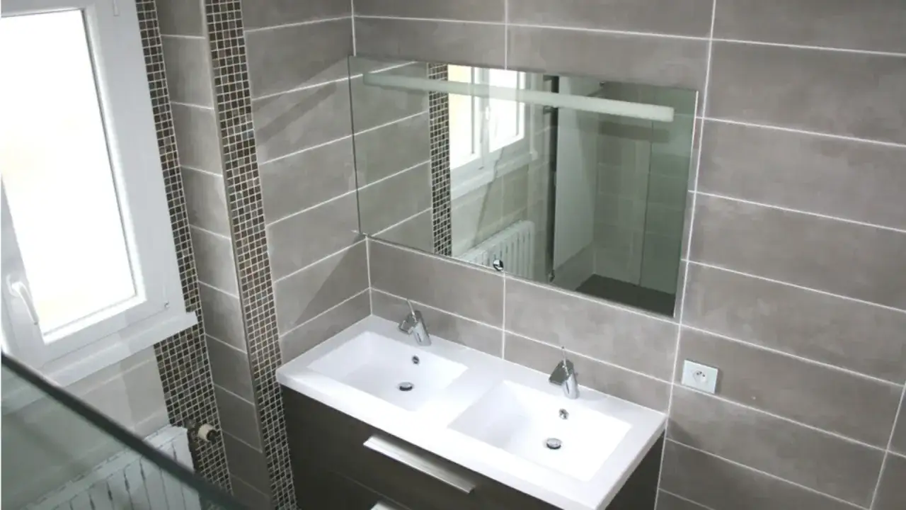 Salle de bain moderne avec double vasque, miroir, fen&ecirc;tre et **carrelage sur placo** gris et mosa&iuml;que.