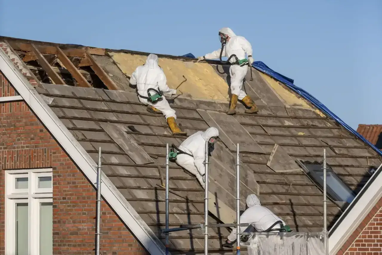 Pracownicy w kombinezonach zabezpieczających wymieniają dach. Możliwe, że korzystają z dotacji na wymianę dachu.