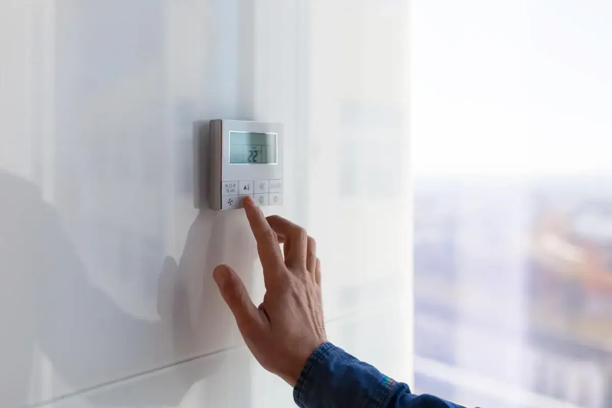 Main tenant ajuste la temp&eacute;rature sur son thermostat connect&eacute;.