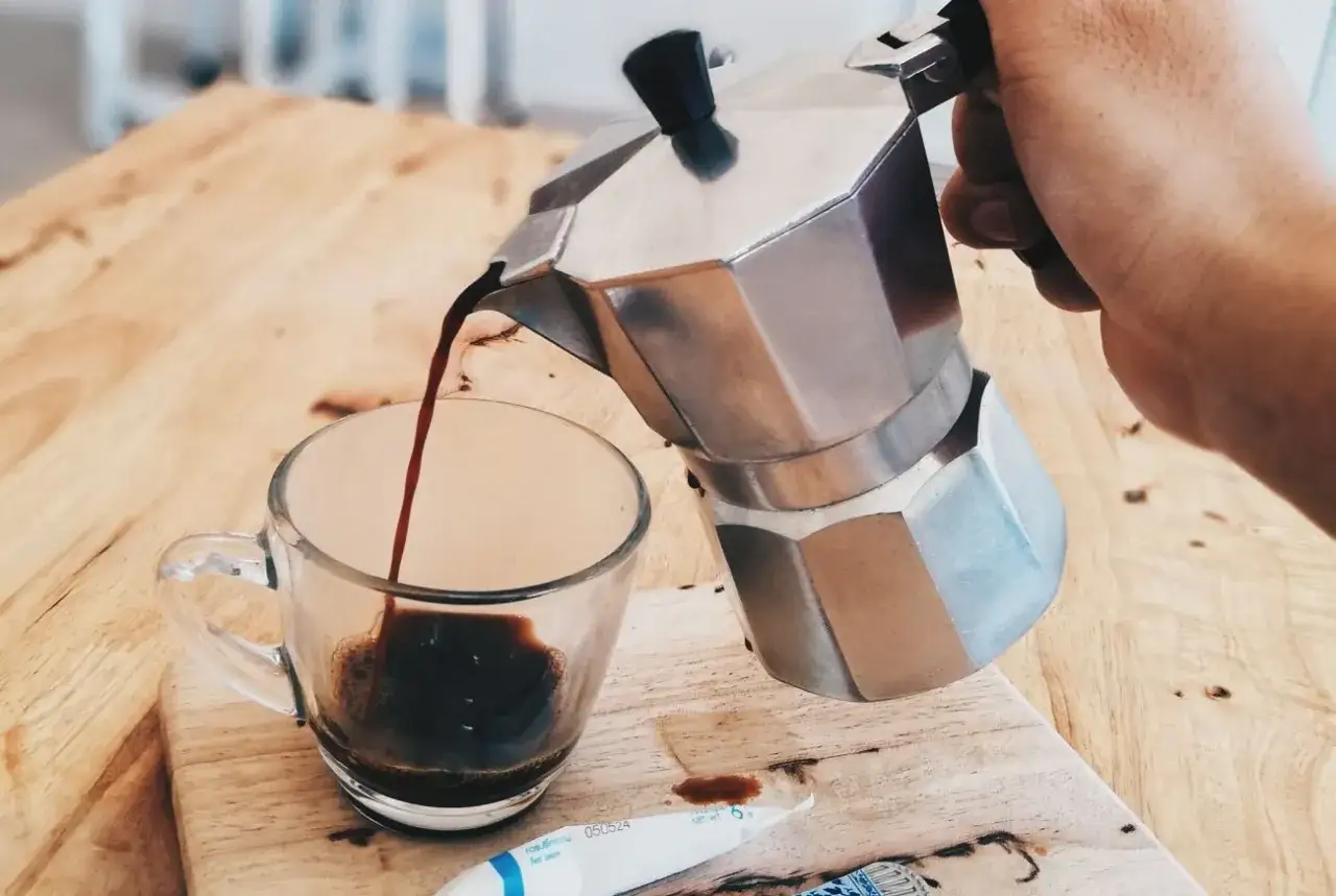 Kawa z kawiarki leje się do szklanki. Idealna do kawiarki jest świeżo mielona kawa.