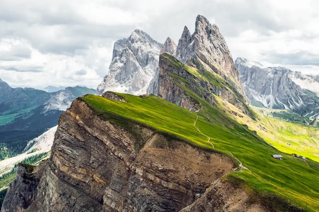 Gr&uuml;ne Almwiesen und zerkl&uuml;ftete Felsen pr&auml;gen die Seceda Wanderung. Ein Pfad schl&auml;ngelt sich durch die Landschaft.