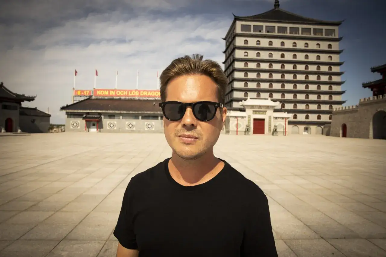 Christian Daun med solglasögon framför en imponerande byggnad i asiatisk stil.