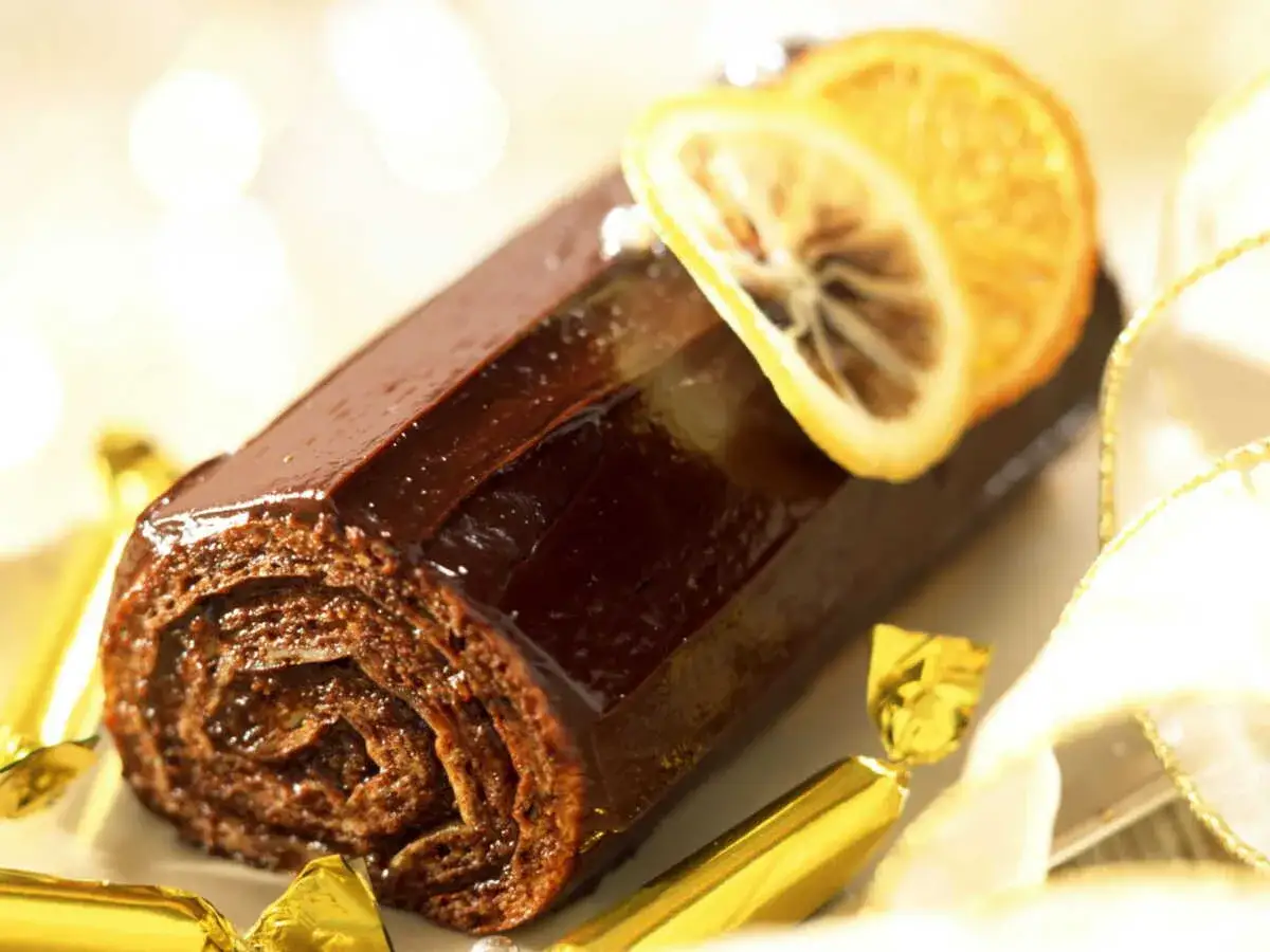 Bûche de Noël au chocolat, garnie d'une tranche d'orange séchée. Un délice croustillant pour les fêtes.