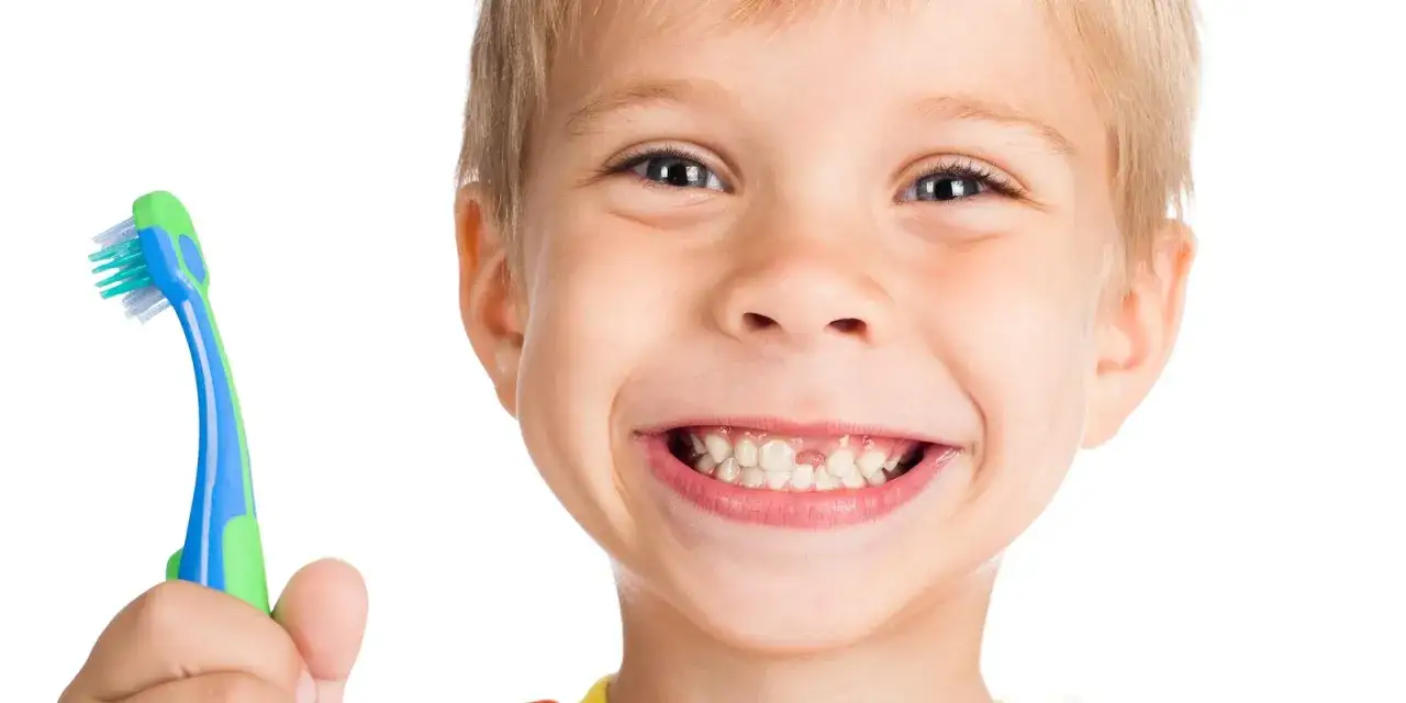 Bambino sorridente con spazzolino, pronto per la pulizia dei denti dei bambini.
