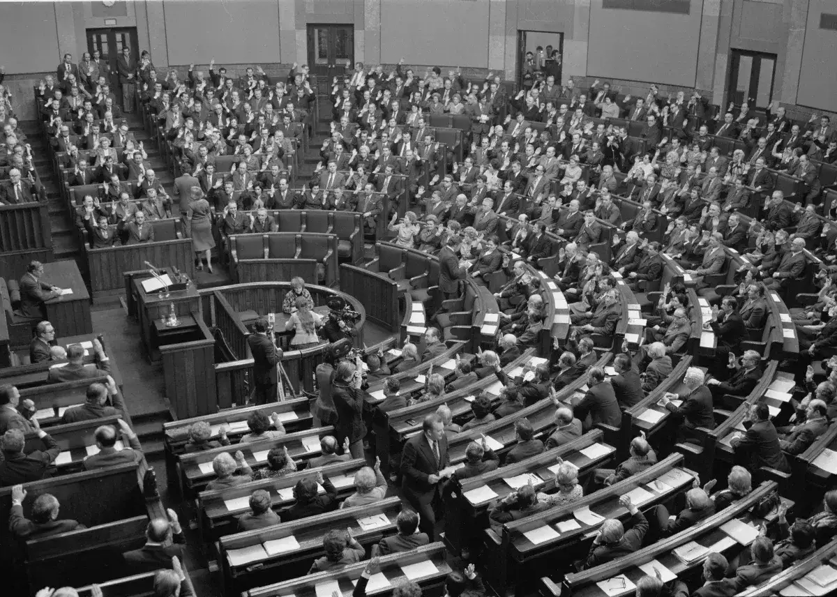Posiedzenie Sejmu, gdzie większość konstytucyjna głosuje, podnosząc ręce. Widać wielu posłów w ławach.