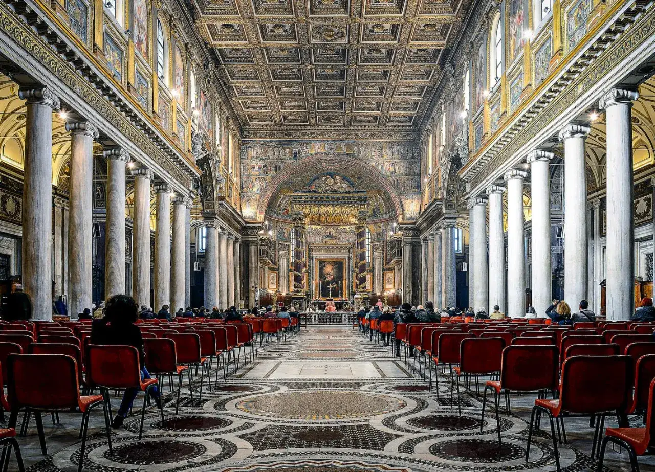 Int&eacute;rieur de la basilique Sainte-Marie-Majeure &agrave; Rome, avec des rang&eacute;es de si&egrave;ges rouges et un plafond orn&eacute;.